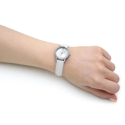 Woman's wrist wearing a silver quartz analog watch with a white band, showcasing the minimalist design.