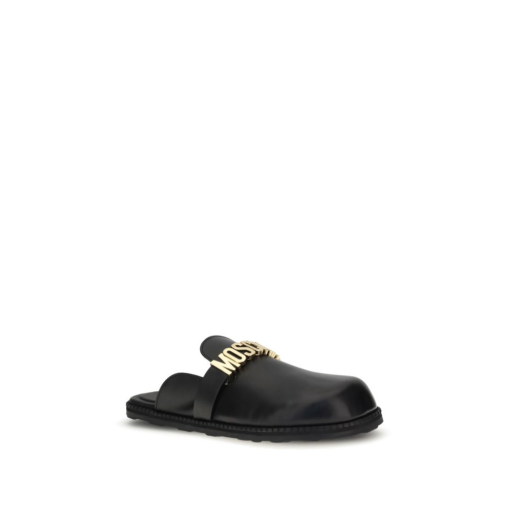Moschino Black Calf Leather Bos Taurus Mules with golden logo plaque and rounded toe, perfect for adding glamour to any look.