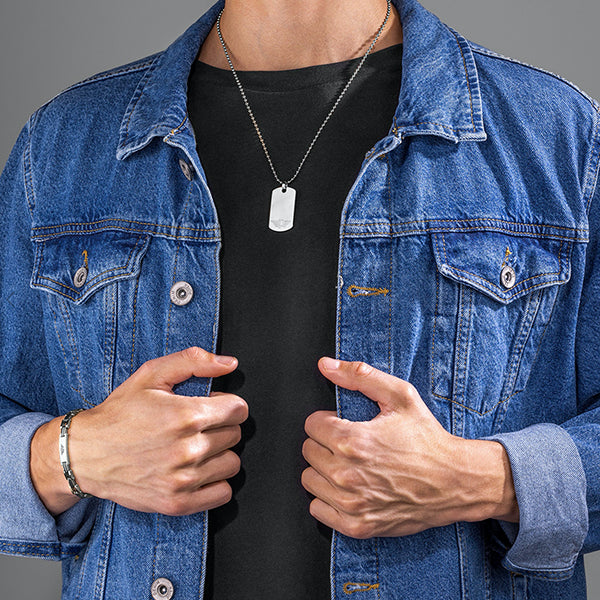 Man wearing blue denim jacket and black shirt with POLICE JEWELS JEWELRY Mod. PEAGB0008701 necklace and silver bracelet.