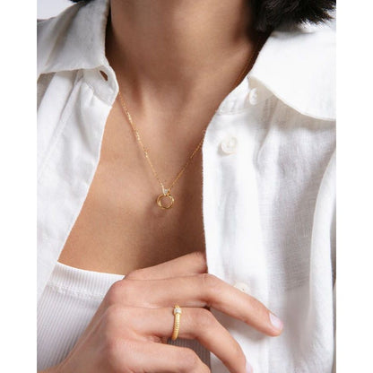 Woman wearing a gold necklace and ring with white shirt.